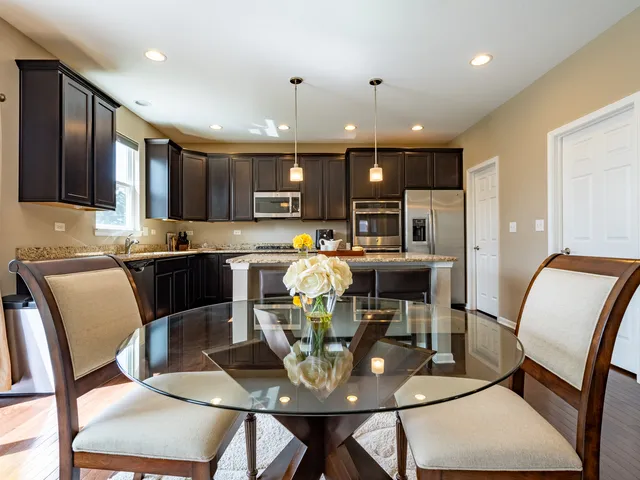 a living room with stainless steel appliances furniture a dining table and kitchen view