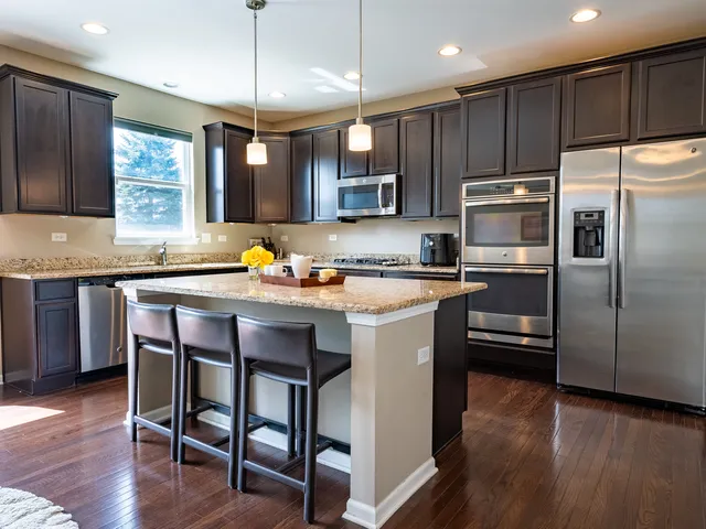 a kitchen with stainless steel appliances granite countertop a sink a stove a refrigerator cabinets and wooden floor