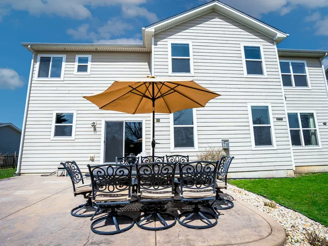a view of a house with patio and wooden chairs