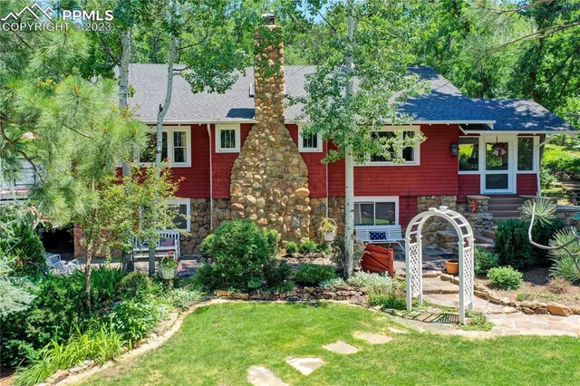 a front view of a house with garden and trees