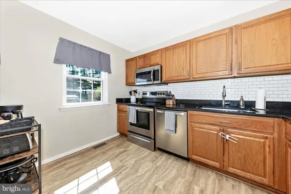 a kitchen with granite countertop wood cabinets stainless steel appliances and a window