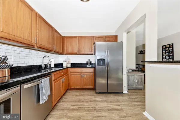 a kitchen with stainless steel appliances granite countertop a refrigerator a stove and a sink