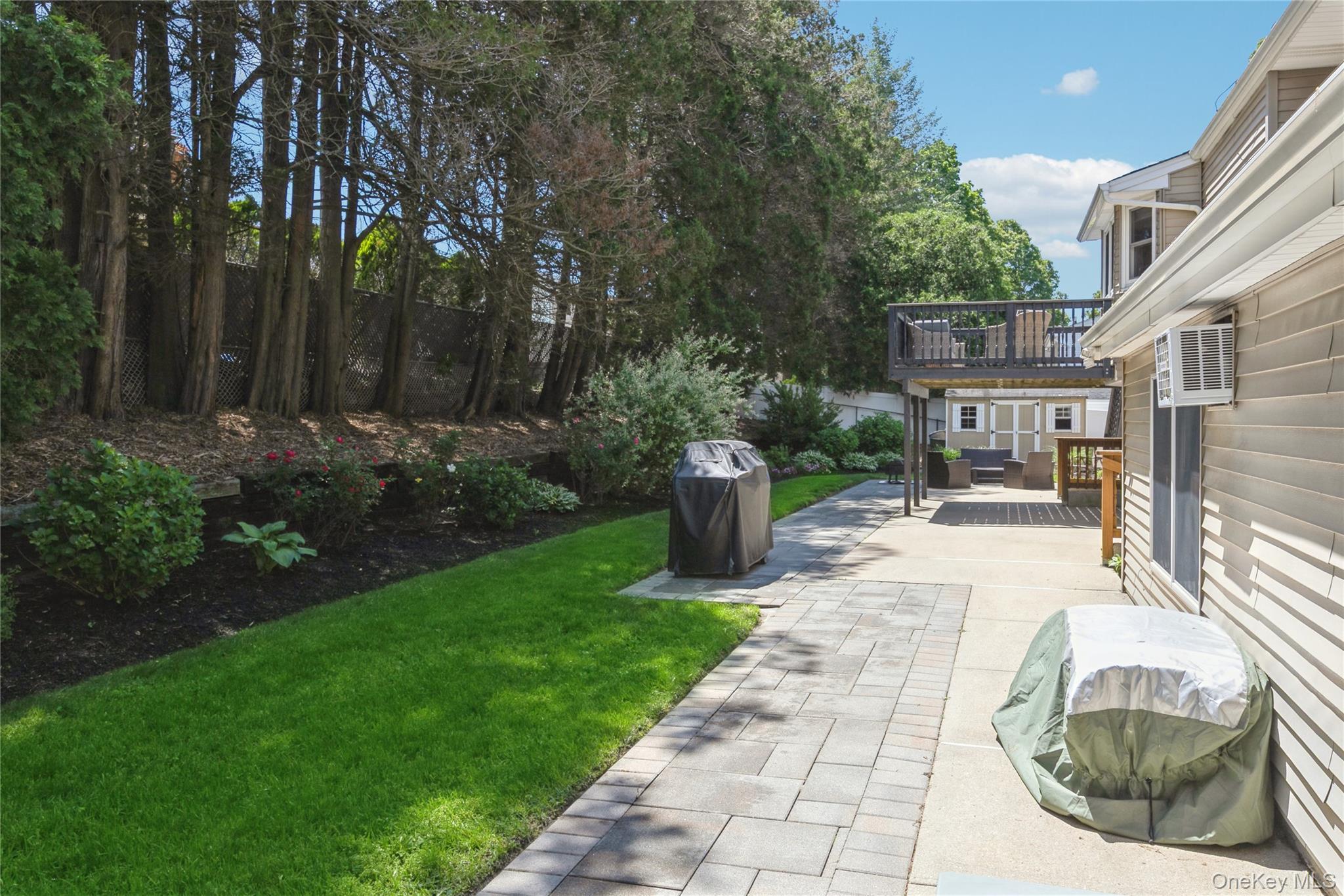 115 Clarendon Road Ronkonkoma, NY 11779 - Photo 36 of 45 Expansive backyard featuring a paver stone pathway, a manicured lawn, and mature perimeter trees