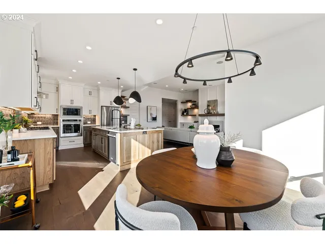 a kitchen with stainless steel appliances granite countertop a sink a stove a dining table and chairs