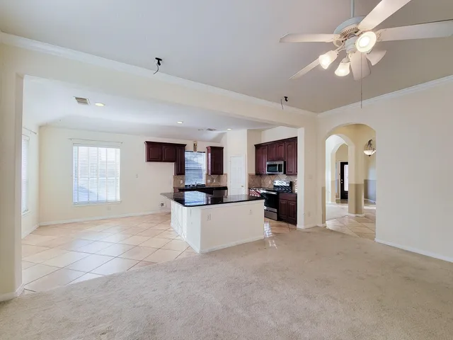 a view of a living room a kitchen and a chandelier fan