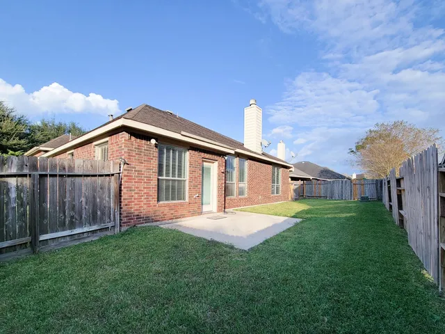 a backyard of a house with wooden fence and large trees