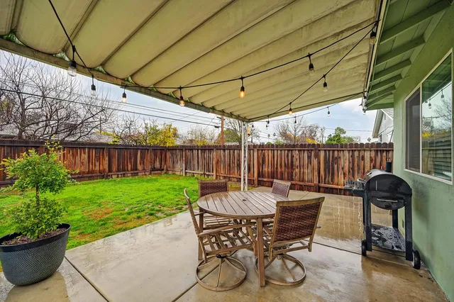 a view of a patio with table and chairs potted plants and covered with wooden fence