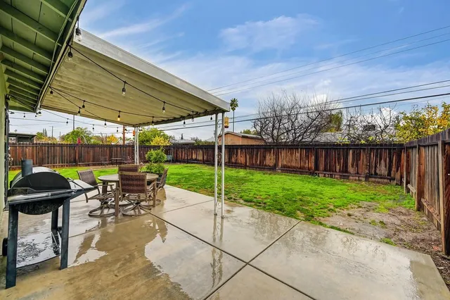 a view of a patio with table and chairs under an umbrella with a small yard
