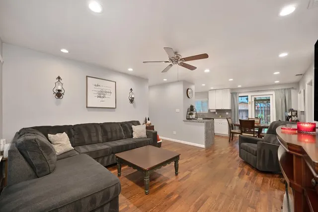 a living room with furniture kitchen view and a wooden floor