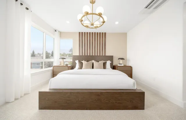 a large white bed in a room next to a window