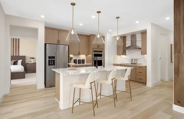 a kitchen with stainless steel appliances kitchen island granite countertop a refrigerator a stove a kitchen island with a dining table and chairs