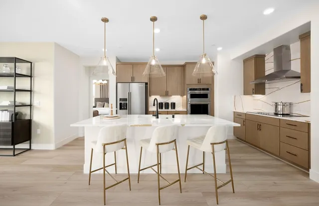 a kitchen with stainless steel appliances kitchen island granite countertop a table chairs and a sink