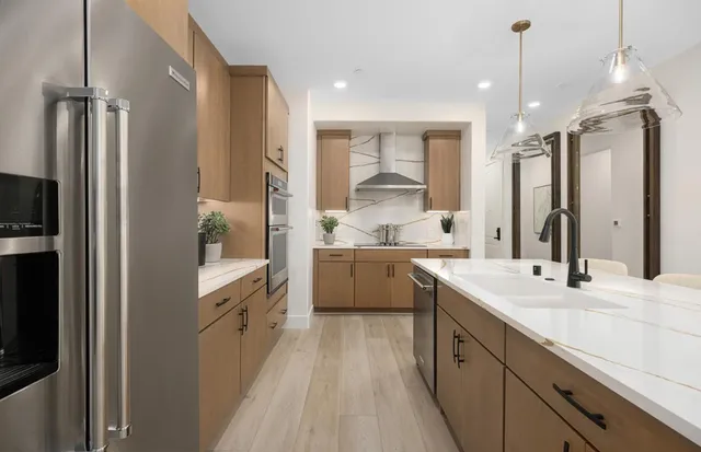 a large kitchen with a sink a counter top space stainless steel appliances and cabinets