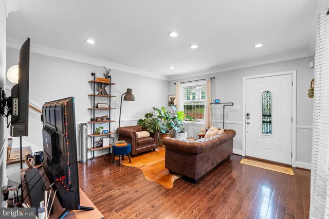 a living room with furniture hard wood floor and a flat screen tv