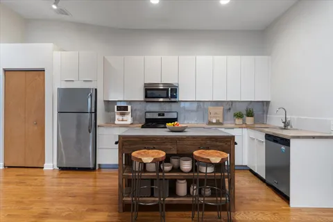 a kitchen with stainless steel appliances granite countertop a refrigerator a stove a sink a dining table and chairs