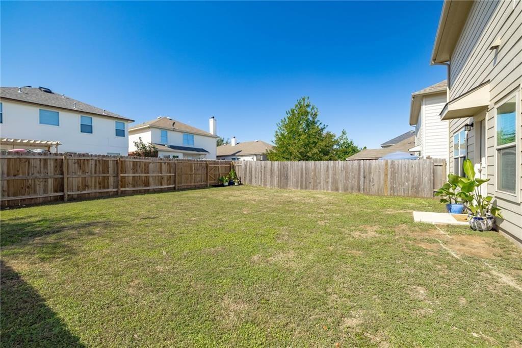 375 Housefinch Loop Leander, TX 78641 - Photo 22 of 28 A spacious grassy lawn sits securely enclosed within a tall wooden privacy fence.