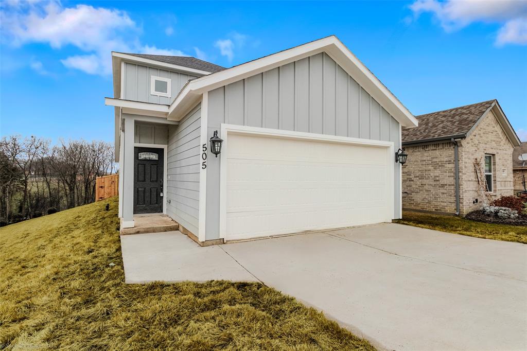 View of front of home featuring a garage, driveway, board and batten siding, and roof with shingles