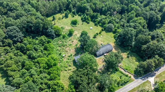 an aerial view of residential house with outdoor space and trees all around