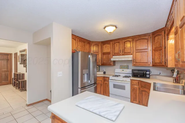 a kitchen with stainless steel appliances granite countertop a stove a sink dishwasher a refrigerator and cabinets with wooden floor