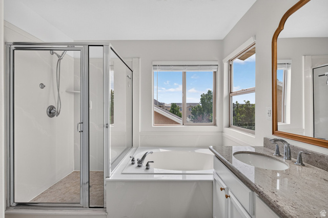 2223 North Pointe Meadow Loop Lehi, UT 84048 - Photo 25 of 56 Bathroom featuring a built-in soaking tub, a glass-enclosed shower, a vanity with a stone countertop and undermount sink, a framed mirror, and multiple windows