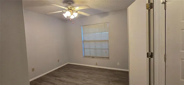 an empty room with windows and fan