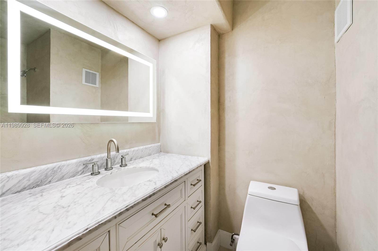 9023 Northeast 4th Avenue Road, Unit 9023 Miami Shores, FL 33138 - Photo 13 of 15 a bathroom with a granite countertop sink a mirror and a toilet