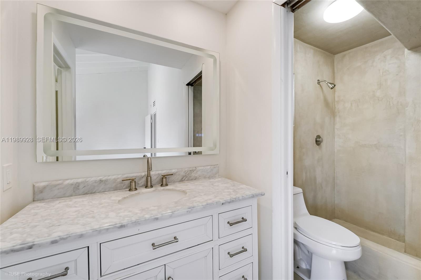9023 Northeast 4th Avenue Road, Unit 9023 Miami Shores, FL 33138 - Photo 9 of 15 a bathroom with a granite countertop sink a toilet and a mirror