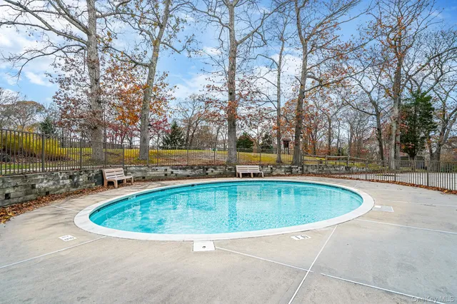 a view of a swimming pool with outdoor seating and covered with trees