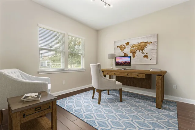 a view of an empty room and kitchen with wooden floor