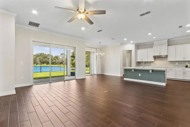 an empty room with wooden floor and a ceiling fan