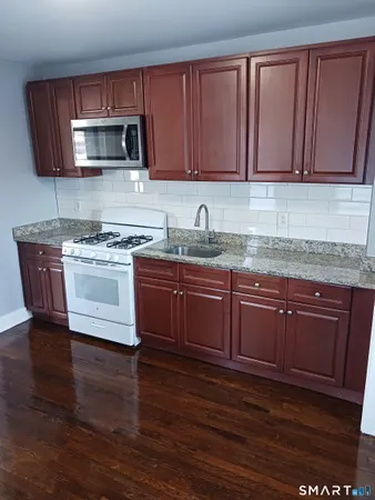 a kitchen with granite countertop wooden cabinets and a stove top oven