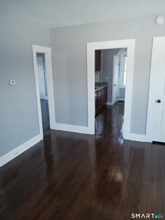a view of a hallway with wooden floor and a bathroom