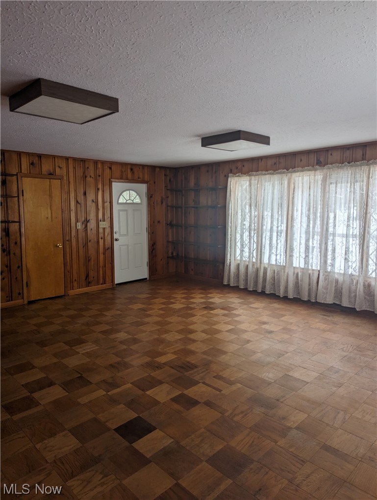 276 Paradise Road Painesville, OH 44077 - Photo 15 of 31 Unfurnished room featuring a healthy amount of sunlight, a textured ceiling, and wood walls