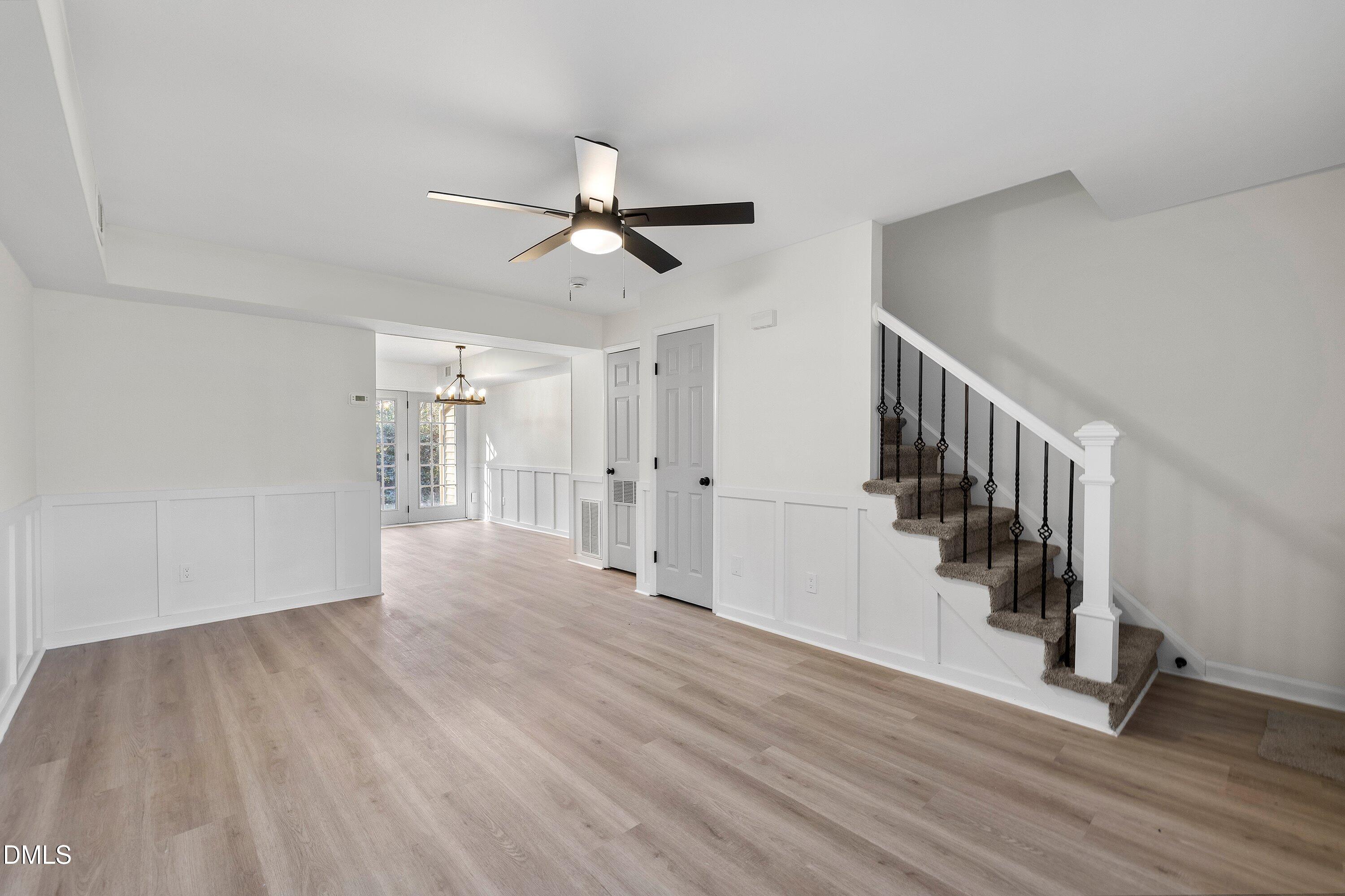4705 Blue Bird Court, Unit E Raleigh, NC 27606 - Photo 20 of 32 a view of an empty room with wooden floor and a ceiling fan