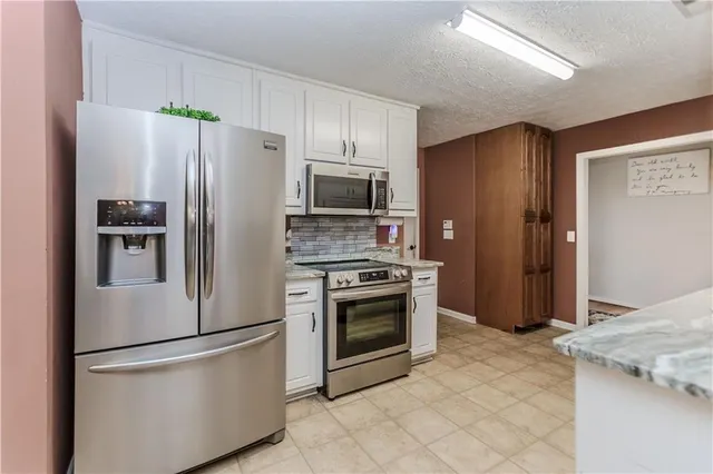 a kitchen with stainless steel appliances granite countertop a refrigerator stove a sink and a refrigerator