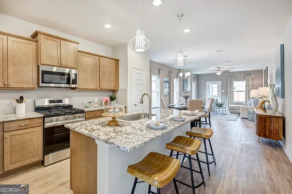 a kitchen with stainless steel appliances granite countertop a stove top oven a sink dishwasher a dining table and chairs with wooden floor