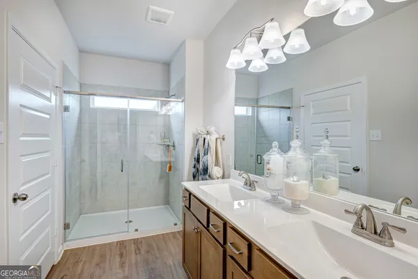 a bathroom with a sink double vanity granite tub shower and a mirror