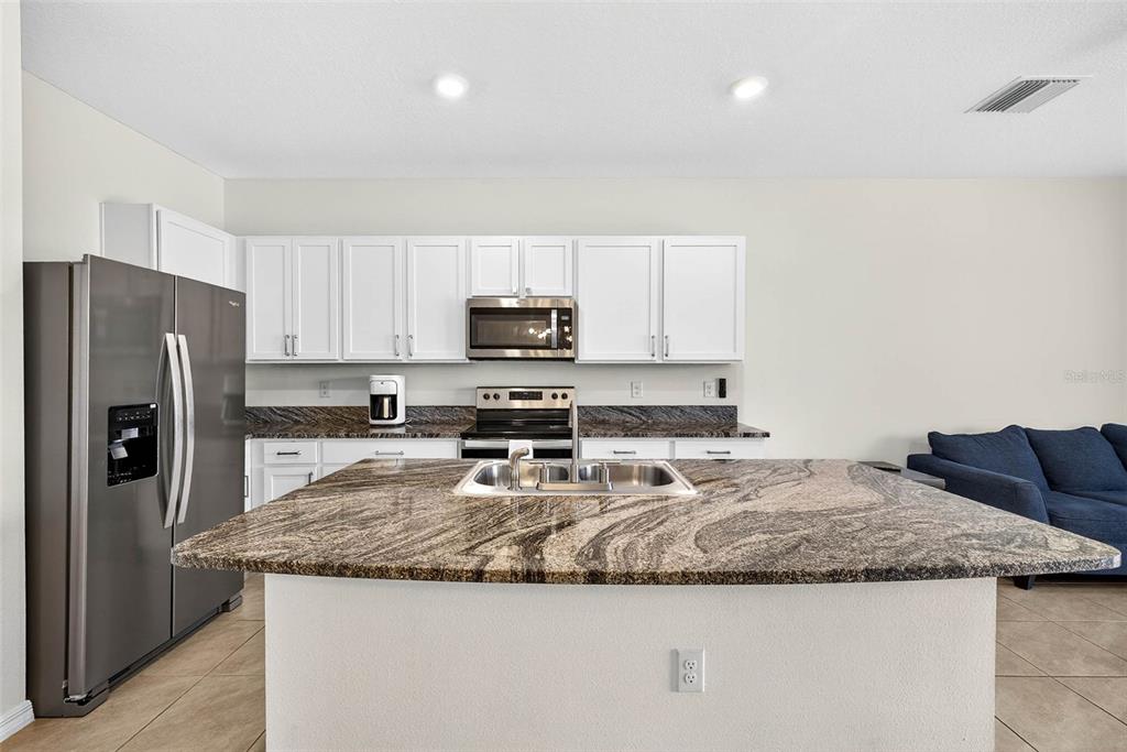 193 Mangrove Shade Circle Apollo Beach, FL 33572 - Photo 11 of 47 a kitchen with granite countertop a refrigerator a stove a sink a microwave and cabinets