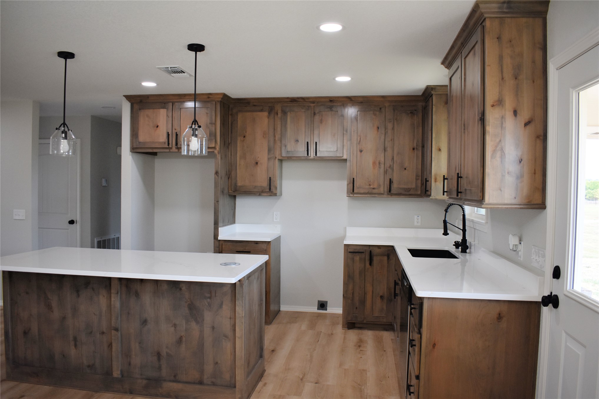 2915 East 2090 Road Hugo, OK 74743 - Photo 4 of 27 Kitchen featuring wood-finish cabinetry, white countertops, a central island, and wood-finish flooring