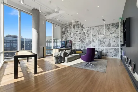 a living room with furniture a flat screen tv and a floor to ceiling window