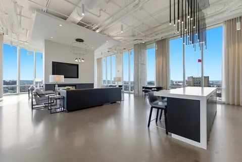 a living room with couches a flat screen tv and kitchen view