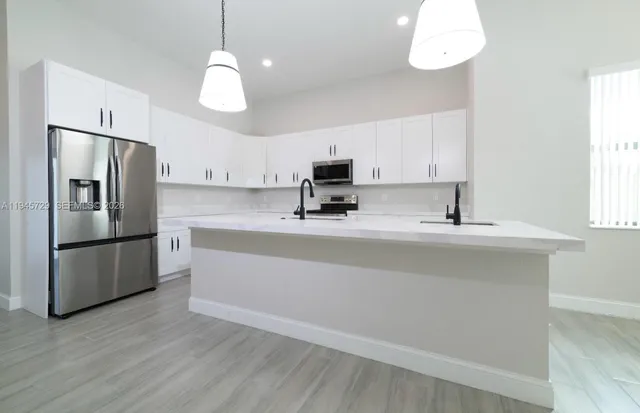 a kitchen with stainless steel appliances granite countertop wooden floors a stove top oven a sink with a dining table and chairs