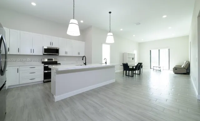 a living room with furniture kitchen view and a large window