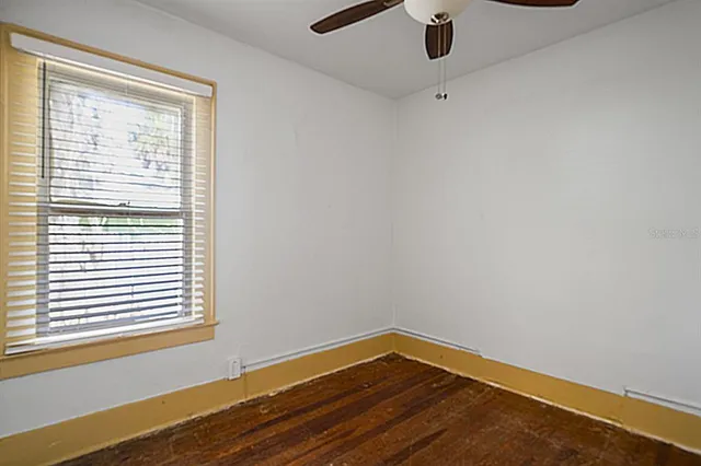a view of an empty room with window and wooden floor