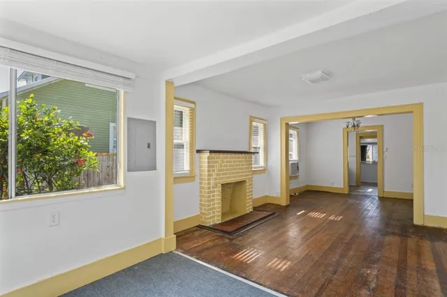 an empty room with windows fireplace and wooden floor