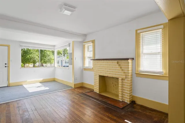 an empty room with windows and fireplace