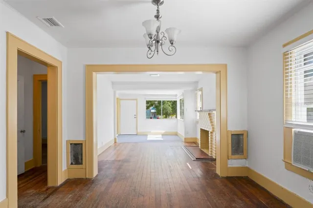 a view of a hallway to a livingroom with wooden floor and windows
