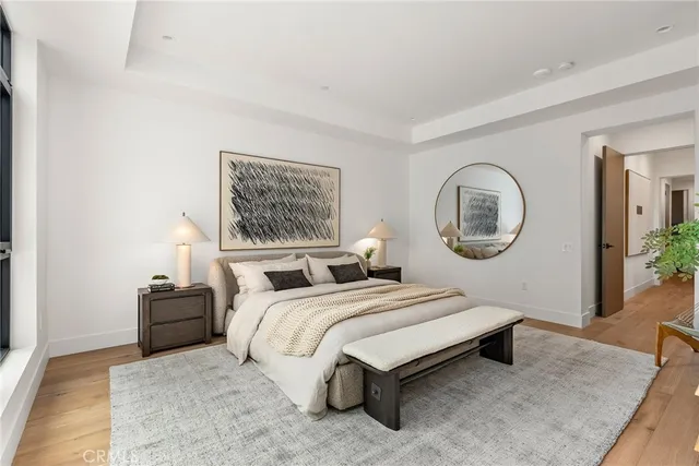 a bedroom with a bed lamp mirror on wall and a large window