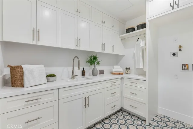 a kitchen with white cabinets and sink