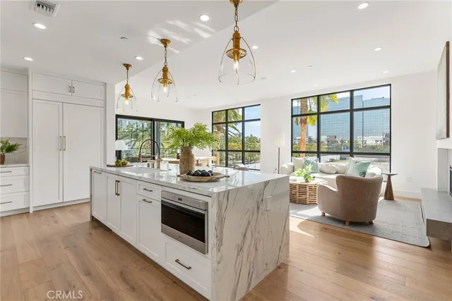 a large kitchen with stainless steel appliances kitchen island granite countertop a stove and a large window with wooden floors